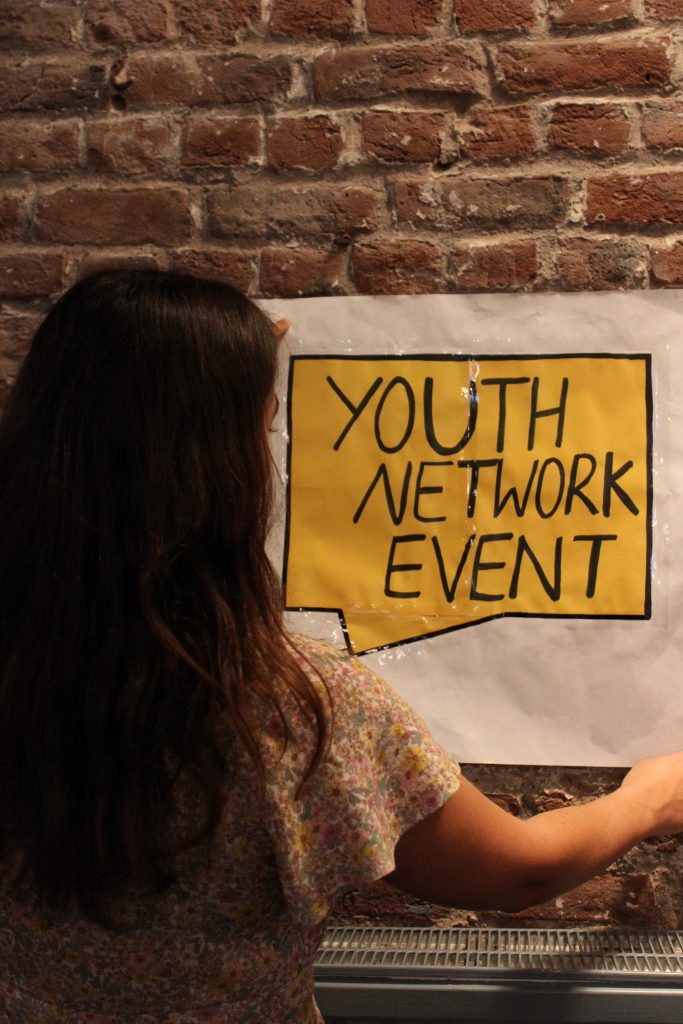 A girl looking at a drawing of the event name- European Youth Event 2022